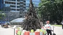 Seorang wanita berpose di depan instalasi yang dijuluki 'Pohon Natal yang Terbakar' di Sydney (18/12/2019). Warga Australia di pantai timur bersiap menghadapi "ancaman baru" ketika gelombang panas disertai dengan angin yang bergolak menurunkan lebih dari 100 kebakaran hutan di kawasan itu. (AFP/Pete