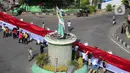 Pelajar SMA membentangkan bendera Merah Putih sepanjang 2,3 kilometer di Jalan Panjaitan dan Jalan Nani Wartabone, Gorontalo, Kamis (23/1/2020). Sebanyak 2.300 pelajar SMA berpartisipasi dalam acara tersebut dengan ikut memegang bendera. (Liputan6.com/Arfandi Ibrahim)