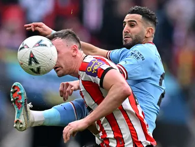 Pemain Manchester City, Riyad Mahrez (kanan) berebut bola dengan pemain Sheffield United, Jack Robinson pada laga semifinal Piala FA 2022/2023 di Stadion Wembley, London, Minggu (23/04/2023) WIB. The Cityzens sukses meraih kemenangan melalui hattrick Mahrez. (AFP/Glyn Kirk)