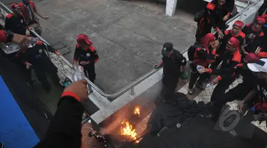 Seorang pria membakar diri dan terjun dari atap stadion Gelora Bung Karno, Jakarta, Jumat (1/5/2015). Sejumlah buruh tampak berusaha memadamkan api dengan air minum. (Liputan6.com/Herman Zakharia)