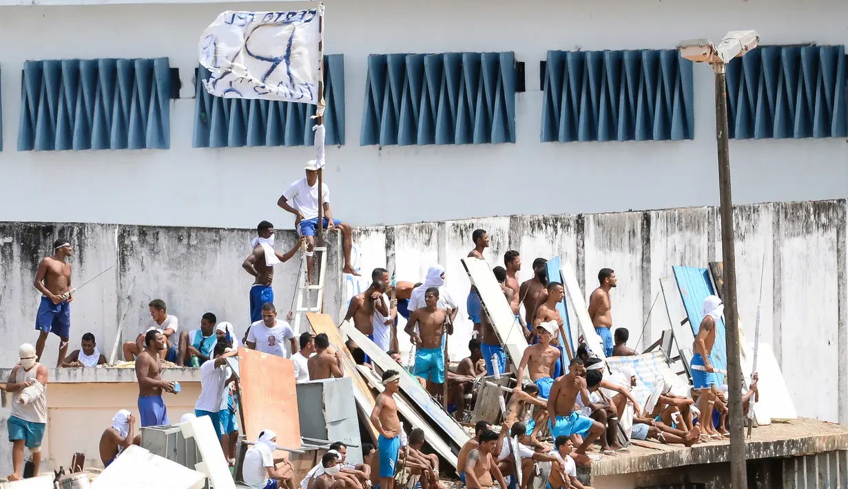 Para tahanan berada diatas atap usai bentrokan antar dua geng narkoba di penjara Alcacuz, Rio Grande do Norte, Brasil, (16/1). Sebagian besar jenazah ditemukan dalam kondisi termutilasi. (AFP Photo/Andressa Anholette)