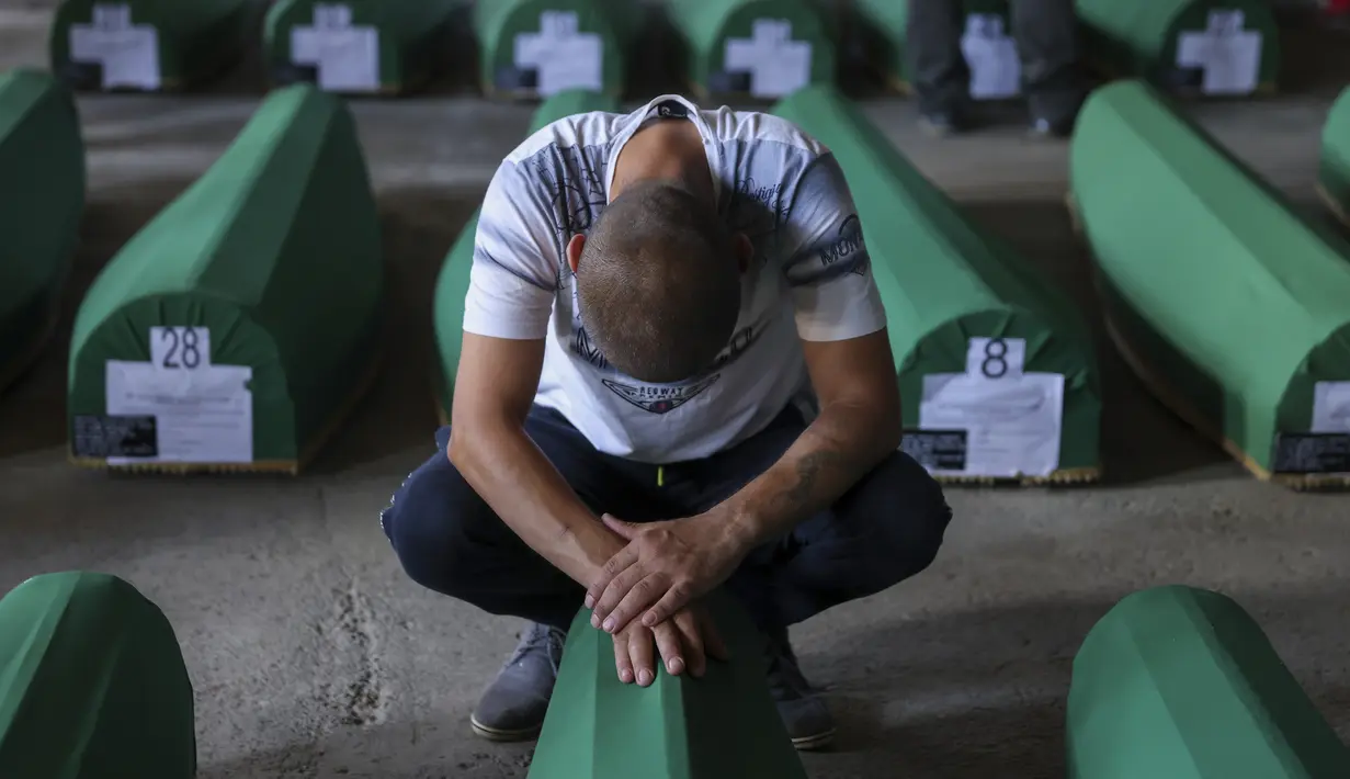<p>Seorang pria muslim berduka di samping peti mati kerabatnya, korban genosida Srebrenica 1995, di Potocari, Bosnia, Minggu (9/7/2023). Sebanyak 30 jenazah korban pembantaian Srebrenica yang baru diidentifikasi, satu-satunya genosida yang diakui di Eropa sejak Perang Dunia II, tiba di Pusat Peringatan di Potocari dimana mereka akan dimakamkan pada 11 Juli. (AP Photo/Armin Durgut)</p>