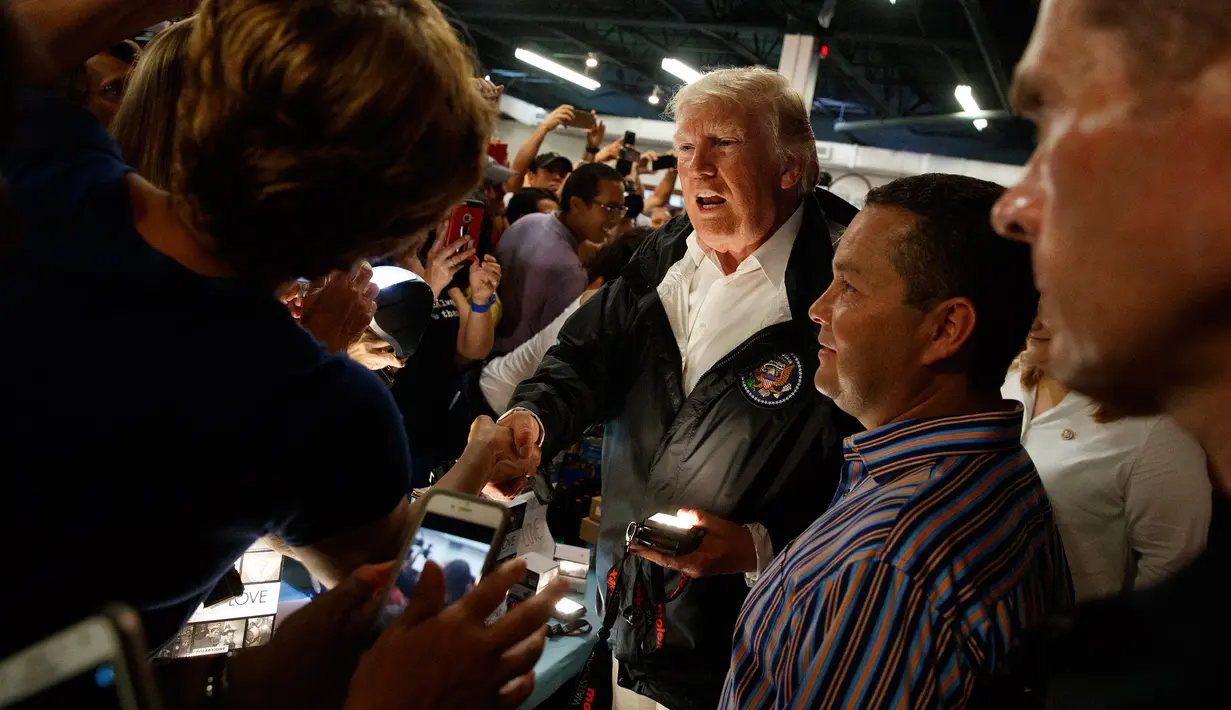 Presiden AS Donald Trump membagikan senter dan perlengkapan lain kepada warga yang terkena dampak Badai Maria di Kapel Calvary, Puerto Rico, Selasa (3/10). Trump meninjau dan melihat kerusakan yang diakibatkan Badai Maria dua pekan lalu. (AP/Evan Vucci)