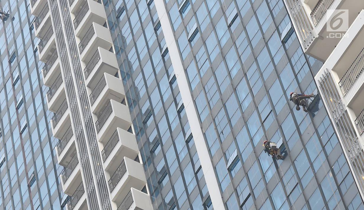 Pekerja membersihkan kaca gedung bertingkat di Jakarta, Kamis (18/10). Kepala Divisi Komunikasi BPJS Ketenagakerjaan Irvansyah Utoh Banja mengatakan, BPJS Ketenagakerjaan menargetkan kepesertaan BPJS Ketenagakerjaan 2018. (Liputan6.com/Immanuel Antonius)
