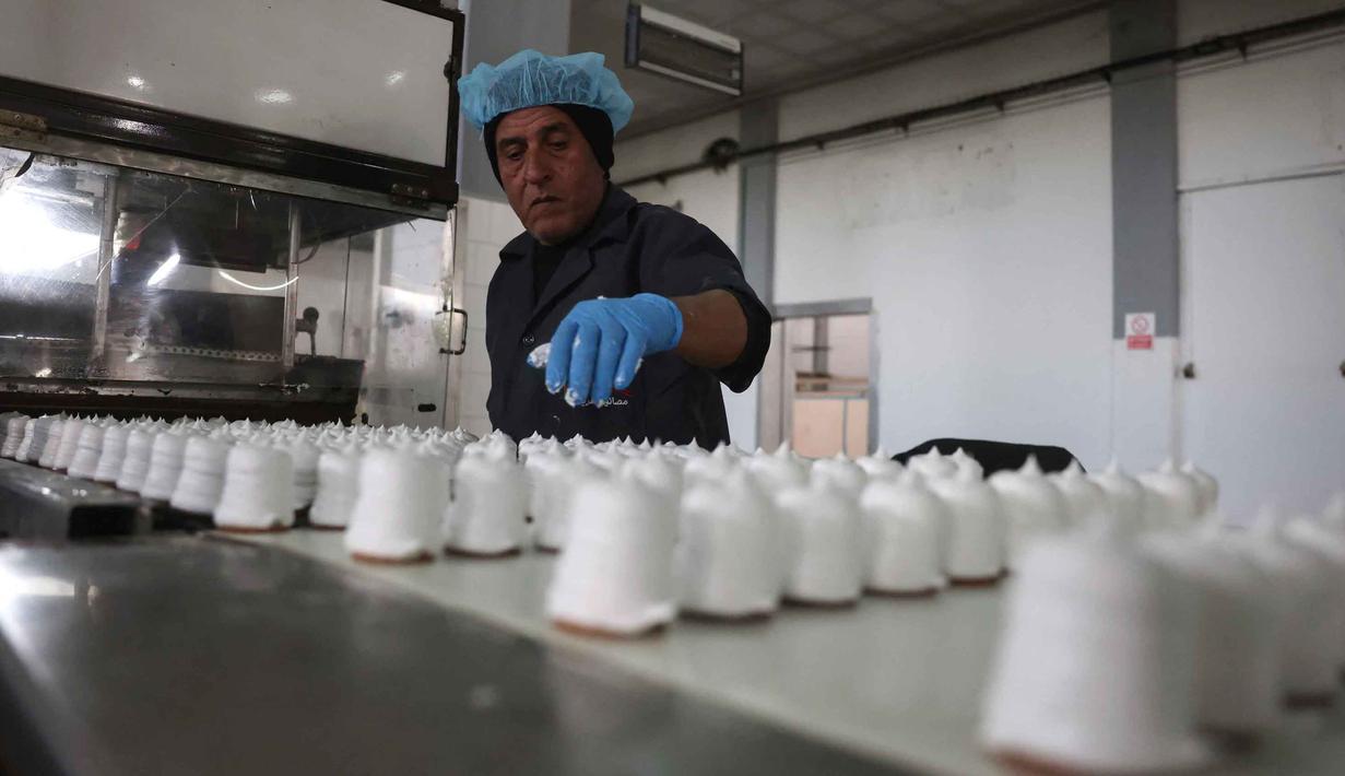 Kembalinya beroperasinya pabrik ini menjadi simbol ketahanan ekonomi di tengah tantangan besar yang dihadapi sektor industri di Gaza. Tampak dalam foto, seorang karyawan Palestina memeriksa kue manis khas lokal yang dikenal sebagai "al-Shatwi" (kue musim dingin) Crimbo, saat pabrik Al-Arees secara bertahap melanjutkan produksinya setelah terhenti akibat perang, di Deir al-Balah, Jalur Gaza tengah pada 12 Januari 2026, (Bashar Taleb/AFP)