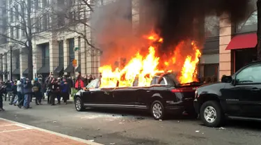 Sebuah mobil limusin dibakar oleh para pengunjuk rasa saat terpakir selama protes pelantikan Presiden Donald Trump di Washington, DC, AS, (20/1). Mobil mewah tersebut menjadi bulan-bulanan massa anti-Trump. (AP Photo/Juliet Linderman)