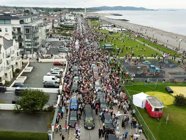 Para penggemar penyanyi Sinead O'Connor berbaris di jalan saat iring-iringan pemakamannya melewati bekas kampung halamannya di Bray, Co Wicklow, Irlandia, Selasa (8/8/2023). Sekitar 3.000 lebih orang memadati jalan sepanjang rute tepi laut di Bray. (Niall Carson/PA via AP)