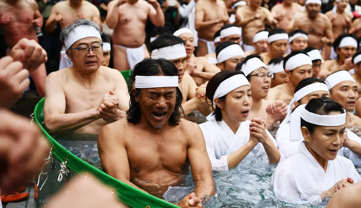 Orang-orang percaya Shinto dari Kuil Teppozu Inari mandi dengan air dingin untuk menyucikan jiwa dan tubuh mereka selama ritual Tahun Baru di Tokyo, Minggu (12/1/2020). Sekitar 100 orang percaya Shinto ambil bagian dalam ritual tahunan tersebut. (AFP/Charly Triballeau)