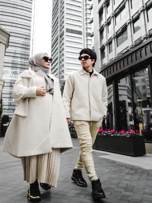 Aurel mengenakan long coat putih gading, yang dipadu dengan pleated long skirt cokelat netral dan sepatu hitam. Begitu juga dengan Atta yang tampil dengan jaket putih gading dengan ritsleting di tengah, celana skinny cokelat netral, dan sepatu hitam. Foto: Instagram.