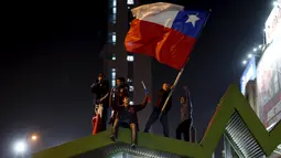 Sejumlah Suporter berada diatas atap mengibarkan bendera nasional Chile merayakan kemenangan Chile atas Uruguay di Copa America 2015 di Santiago, Chile, (25/6/2015). Chile melaju ke semifinal usai mengalahkan Uruguay 1-0. (REUTERS/Pablo Sanhueza)