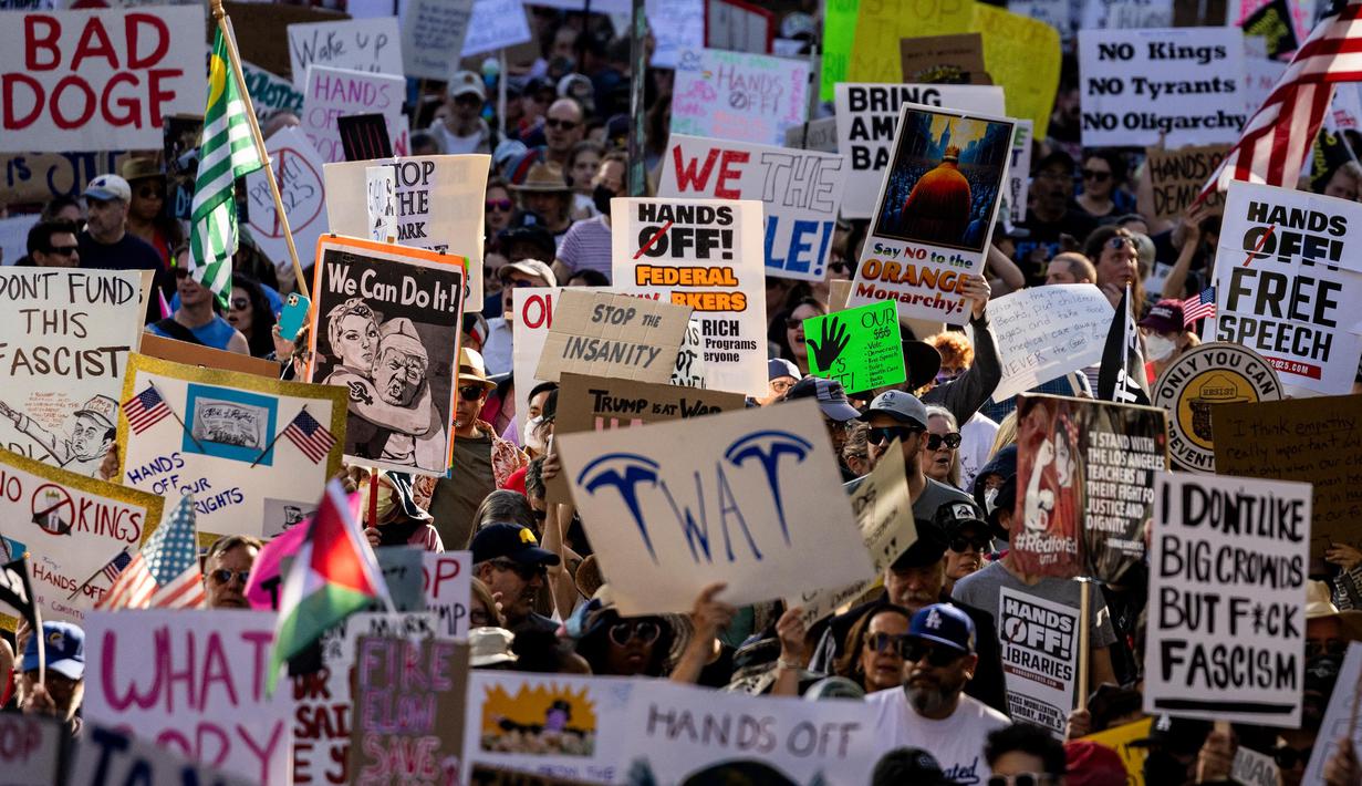 Para pengunjuk rasa mengangkat pamflet selama protes nasional “Hands Off!” terhadap Presiden AS Donald Trump dan penasihatnya, CEO Tesla Elon Musk, di pusat kota Los Angeles, Amerika Serikat pada 5 April 2025. (ETIENNE LAURENT/AFP)