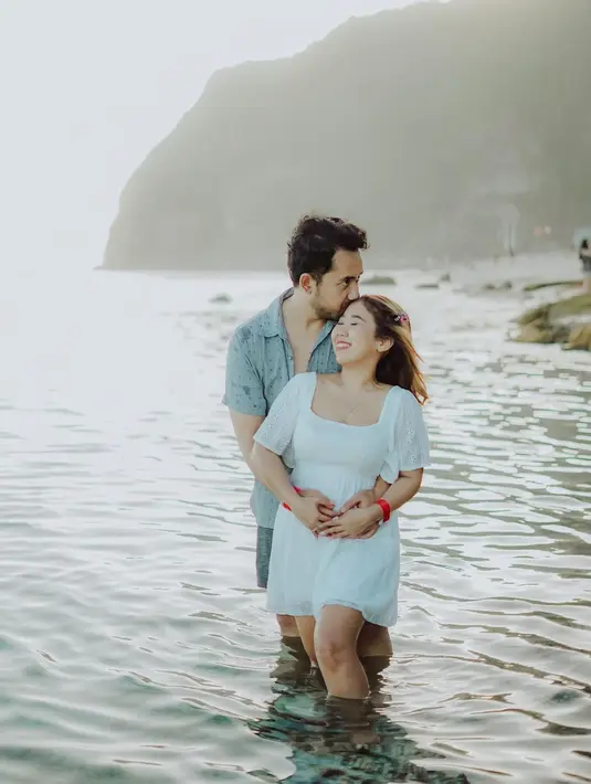 Turut liburan di Bali, Kiky Saputri mengenakan mini dress putih saat berpose bersama suami di pantai. [Foto: IG/kikysaputrii].
