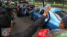 Pengendara ojek online merusak dan melakukan sweeping di kawasan Senayan, Jakarta, Selasa (22/3). Pascabentrok ojek online melakukan sweeping dan perusakan terhadap taksi serta bajaj yang melintas di kawasan tersebut. (Liputan6.com/Immanuel Antonius)