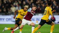 Gelandang serang West Ham, Jarrod Bowen (tengah), berupaya melepaskan diri dari kawalan dua pemain Wolves saat pertandingan Liga Inggris 2024/2025 di London Stadium, Selasa (10/12/2024) dini hari WIB. (Adrian Dennis / AFP)