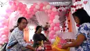 Para wanita menghias balon simbol hati untuk Hari Valentine atau Hari Kasih Sayang di sebuah Tempat Pemungutan Suara (TPS) di Denpasar, Bali, Selasa, 13 Februari 2024. (AP Photo/Firdia Lisnawati)