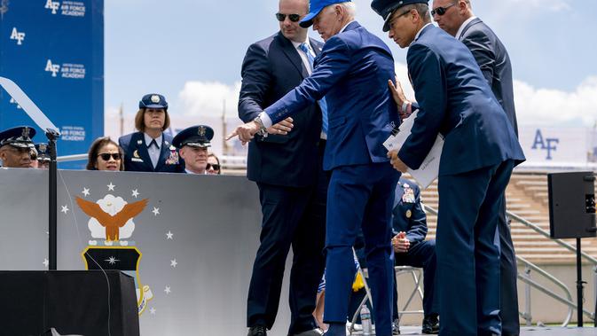 Setelah terjatuh, Biden tampak menunjuk ke arah karung pasir di dekatnya dan berpegangan pada anak tangga, yang menunjukkan bahwa dia tersandung. (AP Photo/Andrew Harnik)