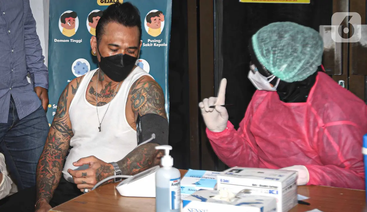 Musikus I Gede Ari Astina alias Jerinx bersiap disuntik vaksin COVID-19 di Biddokkes Polda Metro Jakarta, Sabtu (15/8/2021). Jerinx mengaku telah berkonsultasi dan berdiskusi panjang dengan dokter ahli Virology sampai akhirnya memutuskan untuk menggunakan vaksin Sinovac. (Liputan6.com/Faizal Fanani)