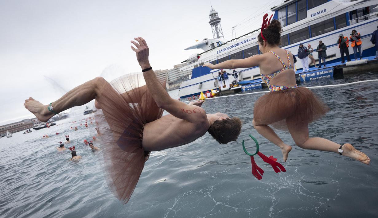 Sejumlah peserta berkostum khas hari Natal melompat ke dalam air dalam ajang Copa Nadal yang berlangsung di Barcelona's Port Vell, Barcelona, Kamis (25/12/2025) waktu setempat. Acara tersebut diikuti lebih dari 450 peserta. (AFP/Josep Lago)