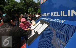 Warga mengisi formulir di Gerai Samsat Keliling di Jalan Kalibata Raya, Jakarta, Senin (11/7). Pasca libur lebaran 2016, gerai Samsat Keliling kembali beroperasi melayani pembayaran pajak kendaraan bermotor. (Liputan6.com/Helmi Fithriansyah)