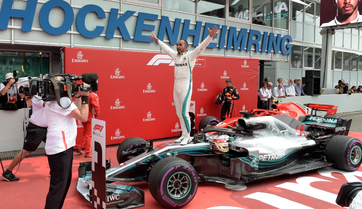 Pembalap Mercedes, Lewis Hamilton berselebrasi setelah berhasil finish pertama pada balapan F1 GP Jerman di Sirkuit Hockenheim, Minggu (22/7). Kemenangan ini diraih secara dramatis karena Hamilton mengawali balapan dari urutan ke-14. (AP/Jens Meyer)