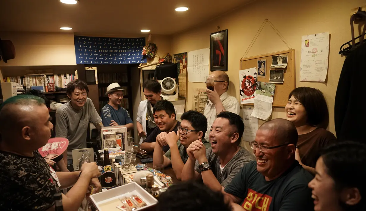 Pengunjung tertawa ketika mereka mendengarkan penghibur Tadashi Yokoda di sebuah bar di Golden Gai di distrik Shinjuku Tokyo (28/7/2019). Gang-gang di kawasan ini merupakan jalan pribadi, bukan jalan umum. (AP Photo / Jae C. Hong)