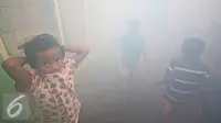 Sejumlah anak berada saat fogging di kawasan padat penduduk di Kebon Nanas, Jakarta, Jumat (15/4). Fogging tersebut dilakukan untuk mencegah berkembangbiaknya nyamuk aedes aegypti penyebab penyakit demam berdarah dengue. (Liputan6.com/Immanuel Antonius)