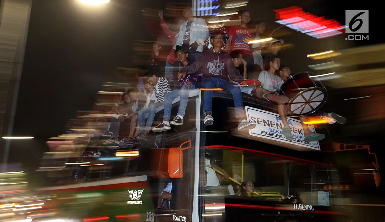 Sejumlah remaja naik berada di atas bus saat melakukan pawai untuk memeriahkan malam takbiran di sepanjang Jalan Mas Mansyur, Tanah Abang, Jakarta Pusat, Kamis (14/6) malam. (Liputan6.com/Johan Tallo)