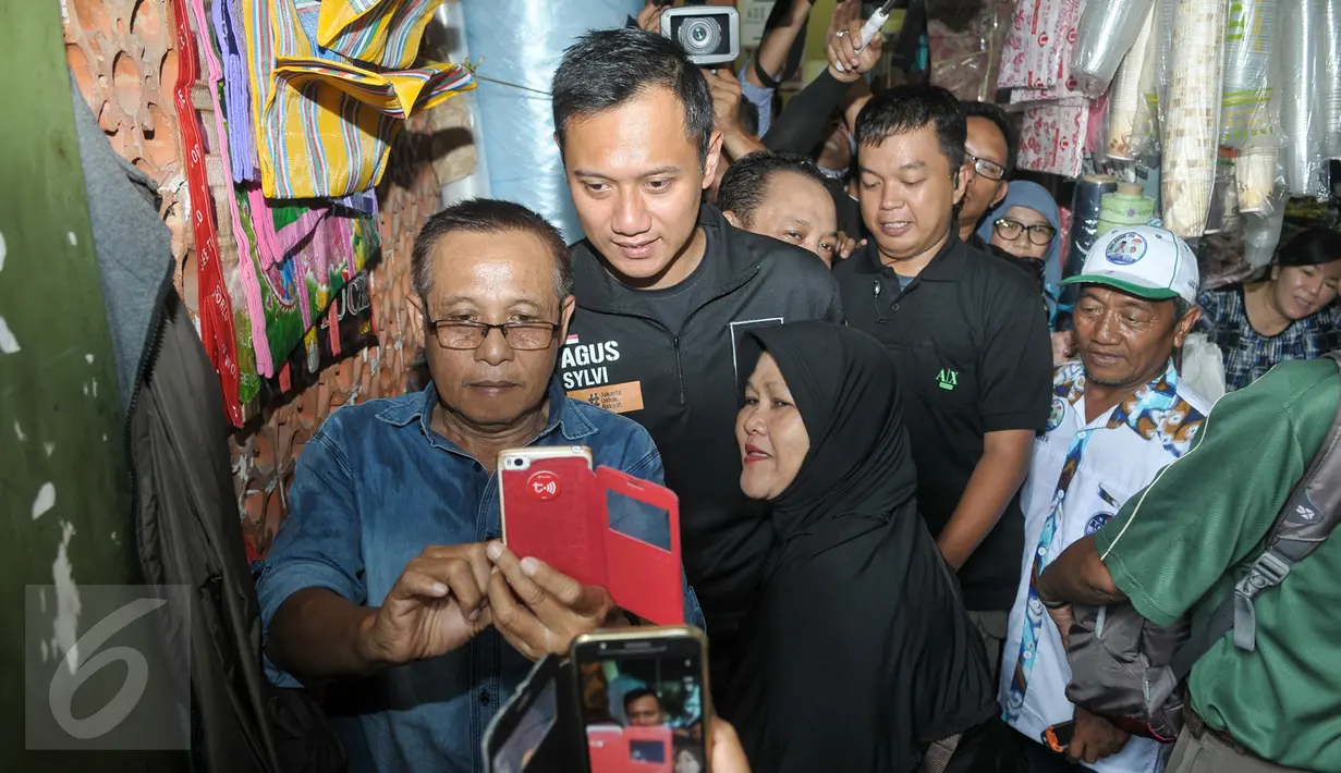Sejumlah warga berebut untuk berfoto bareng dengan Cagub DKI Jakarta Agus Harimurti Yudhoyono di Pasar Senen, Jakarta, Selasa (8/11). Selain meminta doa dan dukungan, Agus juga mendengarkan keluhan para pedagang Pasar Senen. (Liputan6.com/Yoppy Renato)