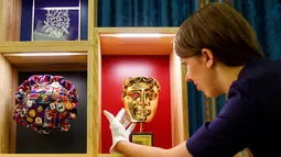 Petugas menunjukkan Penghargaan Kehormatan BAFTA yang diberikan kepada aktor Kenneth Branagh dan Ratu Elizabeth II pada bulan April 2013 jelang pameran Hadiah Kerajaan di Istana Buckingham, London (20/07). (AFP PHOTO / Tolga Akmen)