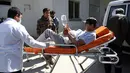Seorang pria muda ditandu ke rumah sakit setelah serangan bom bunuh diri di dekat Universitas Kabul, Afghanistan, (21/3). Sedikitnya 26 orang tewas akibat serangan bom bunuh diri saat perayaan tahun baru Persia. (AP Photo/Rahmat Gul)