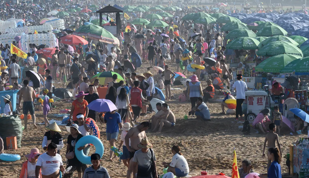 Orang-orang memadati pantai untuk mendinginkan diri di Qingdao, China timur, pada 3 Agustus 2019. Banyak warga di Negeri Tirai Bambu memanfaatkan musim panas dengan mengunjungi pantai untuk mengisi liburan. (Photo by FRED DUFOUR / AFP)