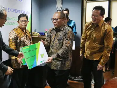 Dirut BPJS Ketenagakerjaan Agus Susanto memberikan kartu peserta usai menandatangani nota kesepahaman, Jakarta, (13/9). Kerjasama dilakukan untuk melindungi para pekerja dan pelaku usaha ekonomi kreatif yang ada di Indonesia. (Liputan6.com/Angga Yuniar)