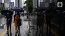 Pejalan kaki menggunakan payung saat hujan di kawasan Jakarta, Selasa (16/2/2021). Setelah memulai vaksinasi COVID-19 tahap pertama dengan sasaran petugas kesehatan, kini pemerintah menargetkan lansia dan petugas pelayanan publik untuk penerima vaksinasi tahap kedua. (Liputan6.com/Johan Tallo)