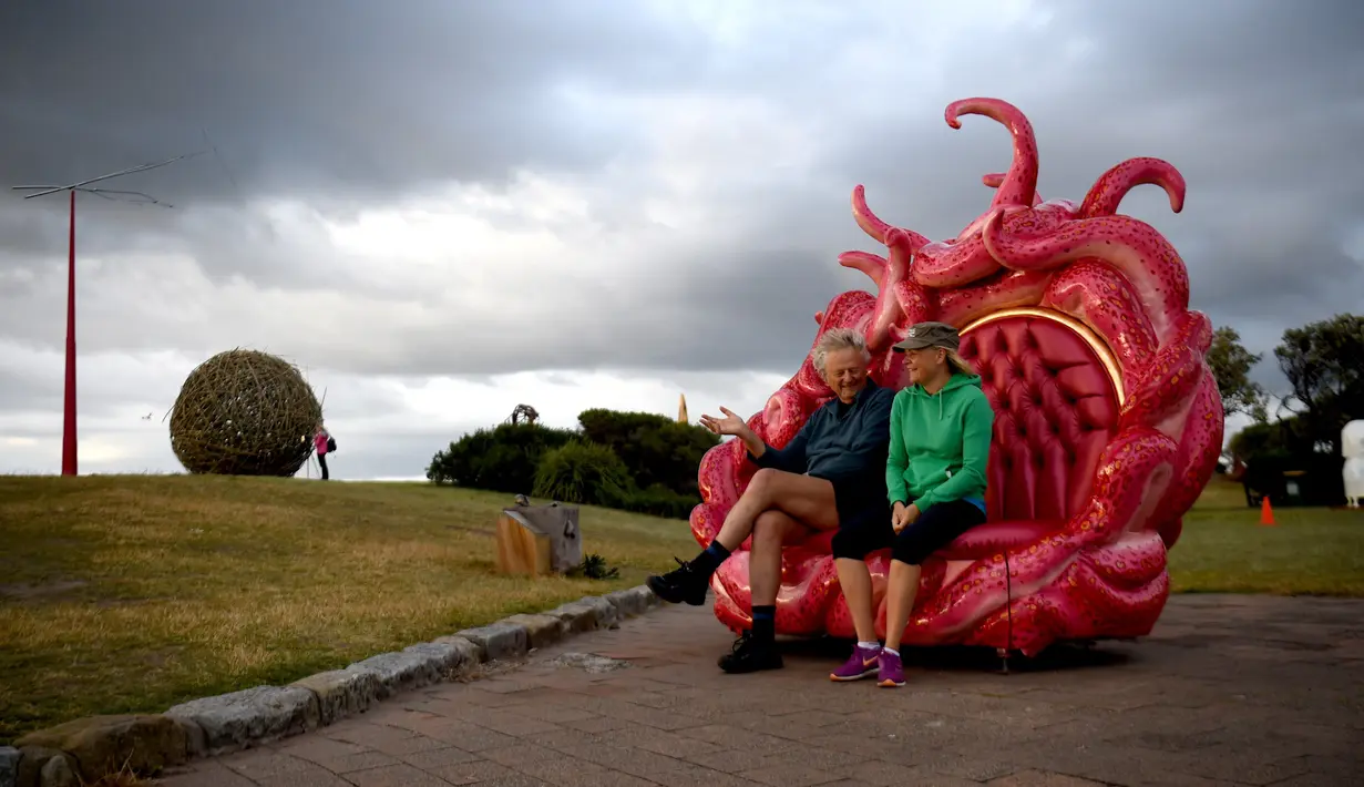Pengunjung duduk di salah satu karya patung yang dipamerkan di pantai Bondi hingga Tamarama di Sydney, Rabu (19/10). Pameran yang bernama ‘Sculpture by the sea’ merupakan pameran patung tahunan diluar ruangan yang terbesar di Australia. (PETER PARKS/AFP)
