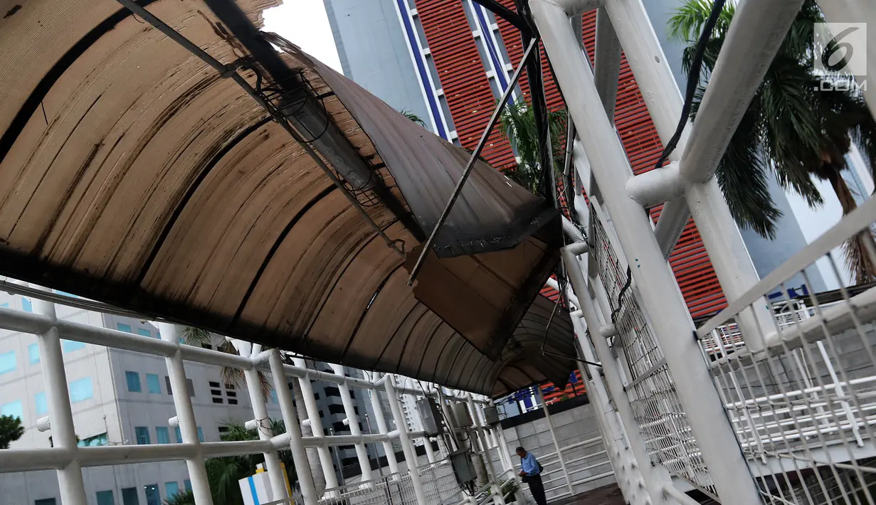 Warga melintasi Jembatan Penyeberangan Orang (JPO) di kawasan Dukuh Atas, Jakarta, Rabu (12/12). Atap JPO Dukuh Atas mengalami kerusakan. (Liputan6.com/JohanTallo)