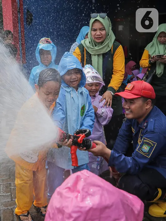 Petugas pemadam kebakaran (Damkar) Kota Tangerang membantu siswa Taman Kanak-Kanak (TK) menyemprotkan air untuk memadamkan api saat edukasi pengenalan profesi Damkar di Kota Tangerang, Banten (22/11/2023). (Liputan6.com/Angga Yuniar)