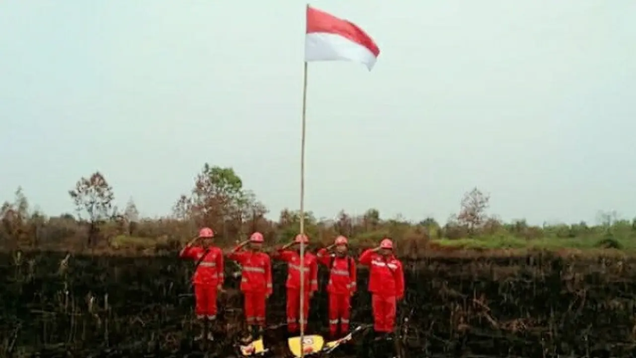 Personel Manggala Agni melaksanakan upacara kemerdekaan Indonesia di tengah lokasi kebakaran lahan.