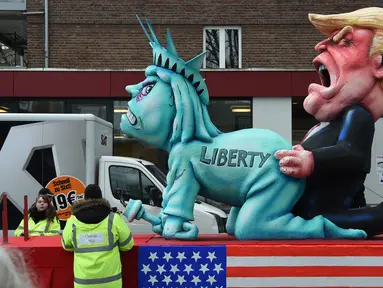 Sebuah patung berbentuk menyerupai Patung Liberty dan Presiden AS ikut dalam karnaval tradisional 'Rose Monday' di Dusseldorf, Jerman Barat, Senin (27/2). Karnaval 'Rose Monday' berisi sindiran satir para pemimpin dunia. (AFP PHOTO / Patrik STOLLARZ)