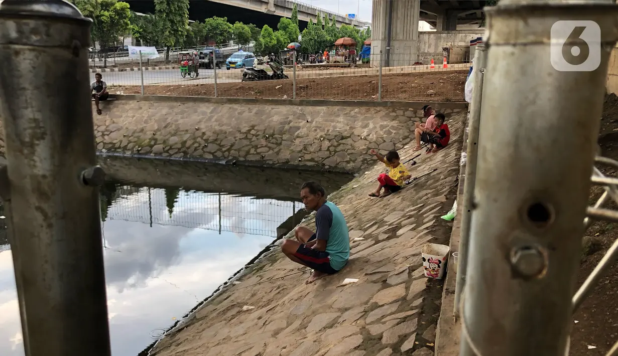 Sejumlah warga memancing ikan di kubangan yang berada di Jalan DI Panjaitan, Jatinegara, Jakarta, Selasa (16/6/2020). Meski telah dipagari, sejumlah warga tetap memancing ikan di lokasi yang merupakan saluran pembuangan tersebut. (Liputan6.com/Immanuel Antonius)