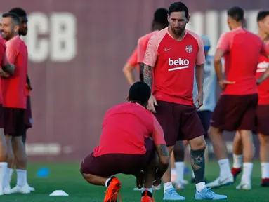 Striker Barcelona, Lionel Messi berbincang dengan rekannya selama sesi latihan di Barcelona, Spanyol (17/9). Barcelona akan bertanding melawan PSV Eindhoven pada grup B Liga Champions di Nou Camp. (AP Photo/Manu Fernandez)