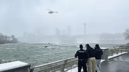 Pihak berwenang memantau sebuah mobil yang terjebak dalam arus deras di tepi Air Terjun Niagara, New York, AS, 8 Desember 2021. Mobil terjebak dalam arus deras sekitar 50 meter dari tepi Air Terjun Niagara. (Larry Kensinger/NC News Service via AP)