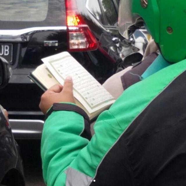 Driver ojek online yang menyempatkan diri membaca Al-Quran saat bekerja | Copyright by KapanLagi.com