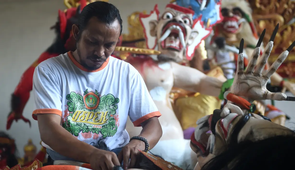 Seorang seniman memasangkan rambut saat menyelesaikan pembuatan patung atau yang dikenal ogoh-ogoh sebelum Perayaan Nyepi di Denpasar, Bali (12/3). Perayaan Nyepi akan jatuh apada tanggal 17 Maret 2017. (AFP Photo/Sonny Tumbelaka)