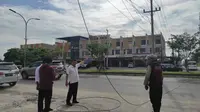 Personel Polresta Pekanbaru mendatangi lokasi kabel menjuntai yang membuat dua pelajar terjatuh dari sepeda motor. (Liputan6.com/M Syukur)