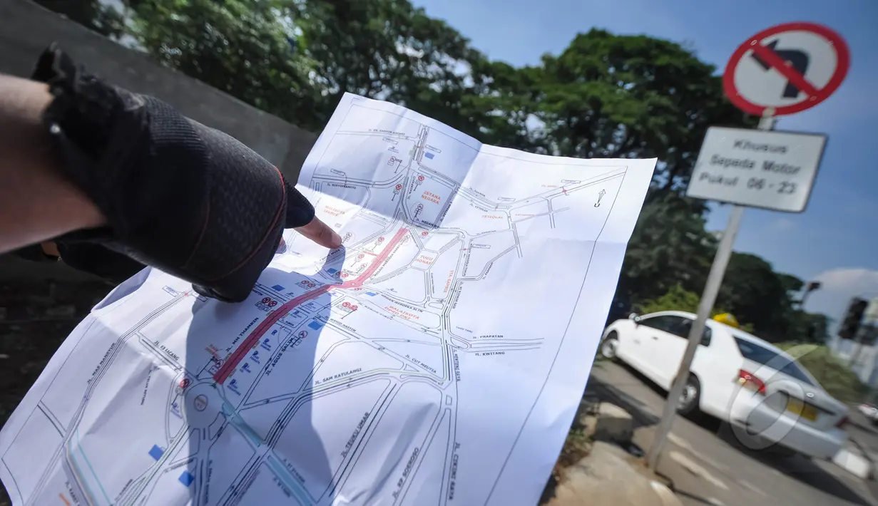 Petugas saat menujukan peta lokasi rambu larangan motor di Jalan Abdul Muis, Jakarta, Senin (6/4/2015). Pengendara sepeda motor diizinkan melintas mulai pukul 23.00 hingga 06.00 WIB. (Liputan6.com/Faizal Fanani)
