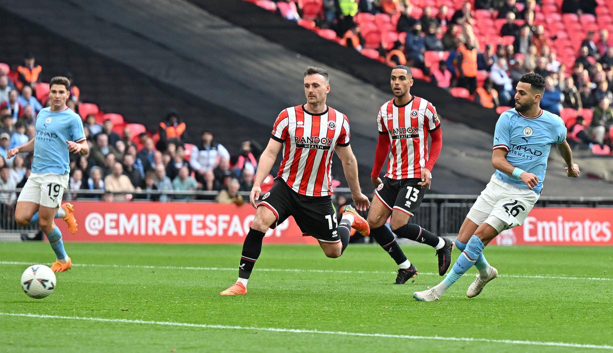 Pemain Manchester City, Riyad Mahrez (kiri) mencetak gol kedua timnya melalui tendangan penalti pada laga semifinal Piala FA 2022/2023 melawan Sheffiled United di Stadion Wembley, London, Minggu (23/04/2023) WIB. The Cityzens sukses meraih kemenangan melalui hattrick Mahrez. (AFP/Glyn Kirk)