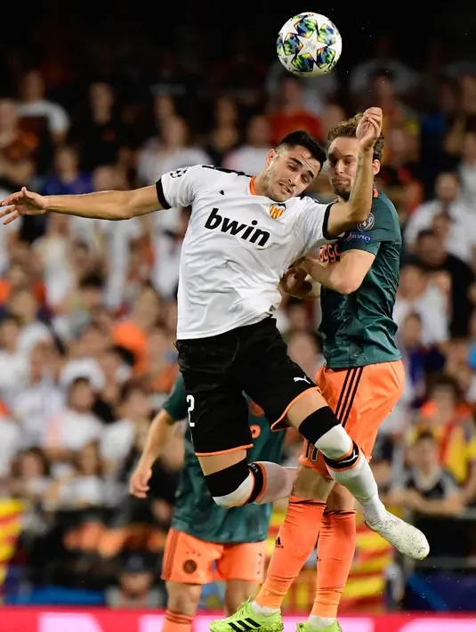 Penyerang Valencia, Maxi Gomez berebut bola dengan bek Ajax Amsterdam, Daley Blind pada lanjutan pertandingan grup H Liga Champions di stadion Mestalla, Spanyol (2/10/2019). Ajax menang telak 3-0 atas Valencia. (AFP Photo/Javier Soriano)