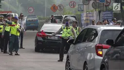 Petugas polisi lalu lintas memberhentikan kendaraan saat pemberlakuan sistem ganjil genap di pintu masuk Gardu Tol Cibubur 2, Jakarta, Senin (16/4). Aturan ganjil genap ini diujicobakan di Gerbang Tol pada  Senin 16 April 2018.(Liputan6.com/Faizal Fanani)