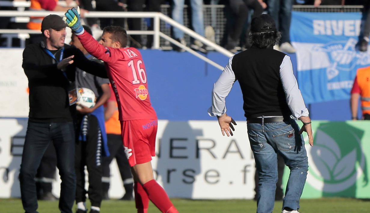 Kiper Bastia, Jean Louis Leca (2kiri) mengusir suporter dari lapangan saat timnya melawan Lyon pada laga Ligue 1 Prancis di Armand Cesari stadium, Bastia, (16/4/2017). Laga ini akhirnya dihentikan LFP. (AFP/Pascal Pochard-Casabianca)