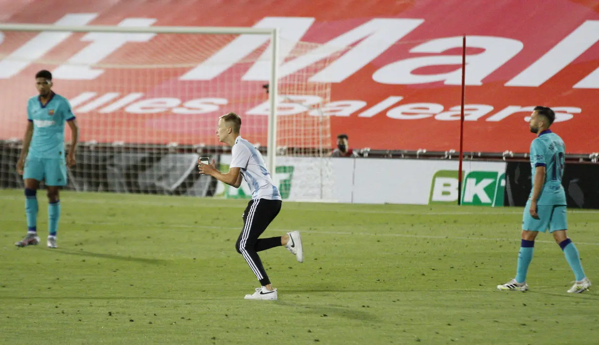 Seorang penyusup (tengah) masuk ke lapangan saat pertandingan La Liga antara Mallorca dengan FC Barcelona di Son Moix Stadium, Palma de Mallorca, Spanyol, Sabtu (13/6/2020). Dalam pertandingan tersebut Barcelona mengalahkan Mallorca dengan skor 4-0. (AP Photo/Francisco Ubilla)